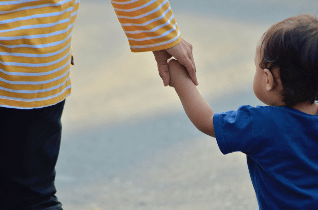 little boy holding parent hand.