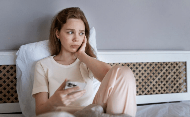 anxious woman in bed with smartphone
