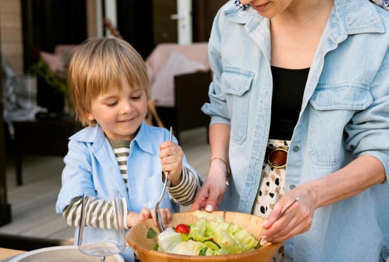 A woman and child engaging in meal prep, as they prepare a salad together.