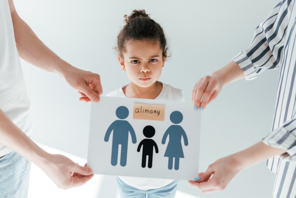 selective focus of parents holding paper with drawn family and alimony lettering near adopted