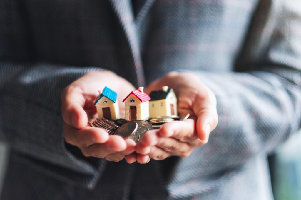 Closeup image of family lawyers holding coins and house models in hands