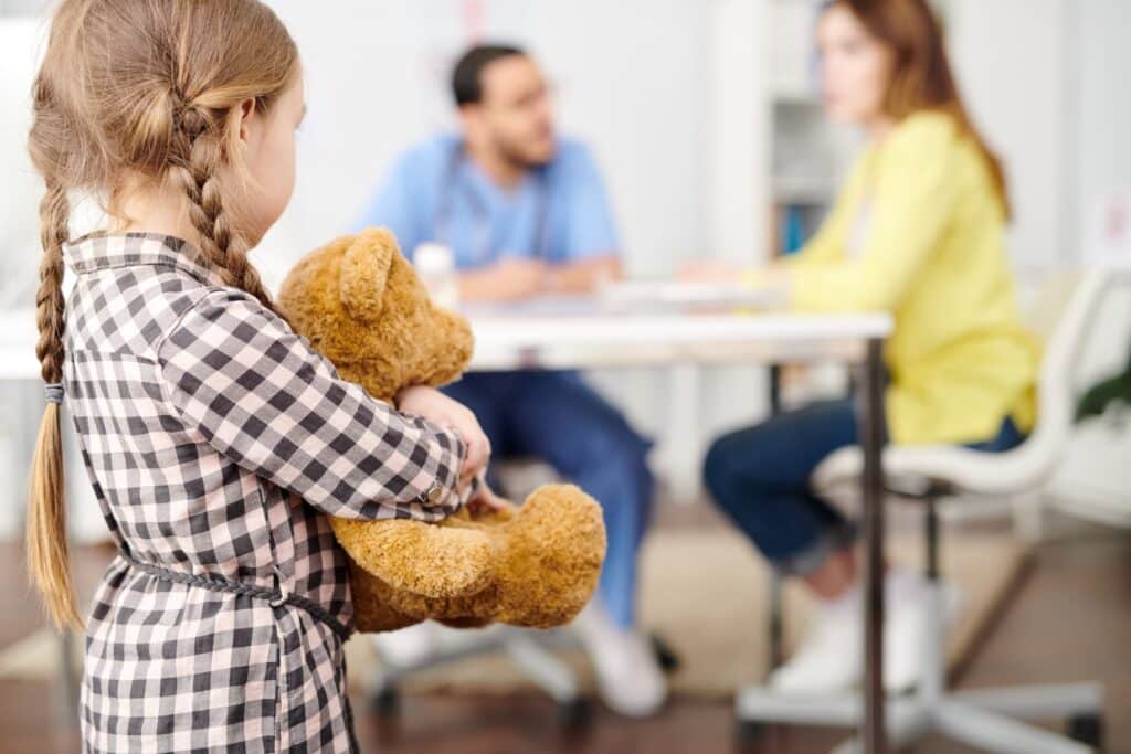 a kid holding her stuff toy while in the corner room