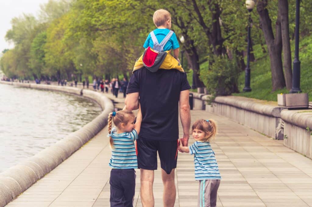 father carrying his three children at the park