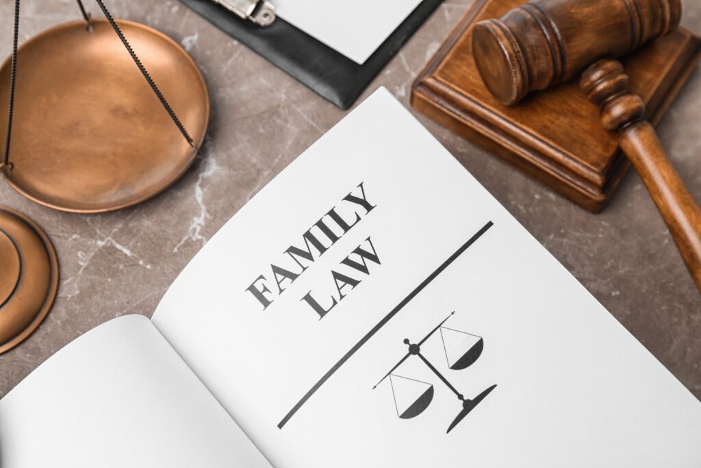 Open book with words FAMILY LAW, scales of justice and gavel on table, closeup