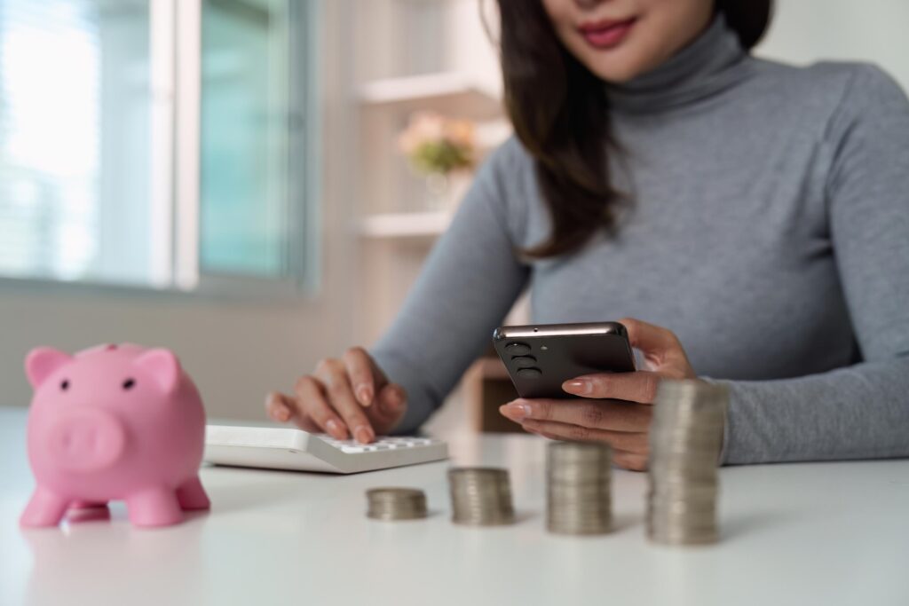 Financial Empowerment: Woman Managing Savings with Smartphone and Calculator