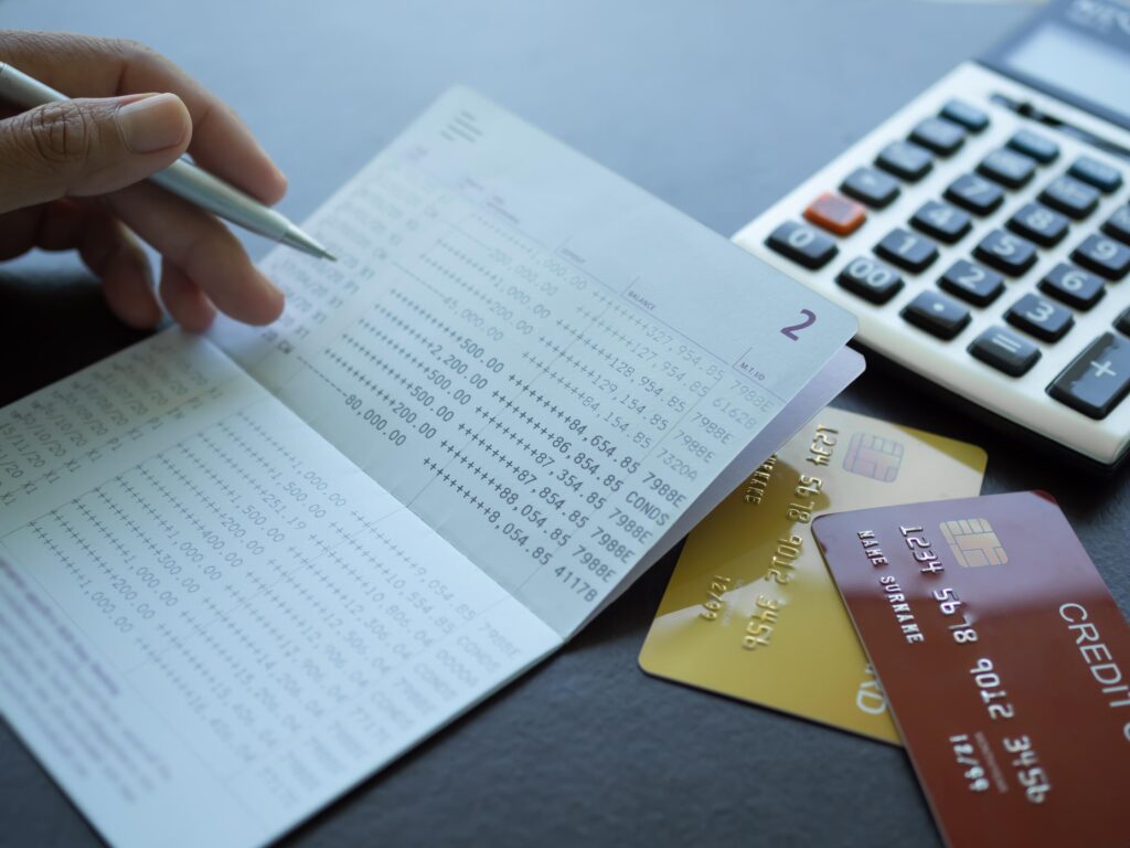 Finger holding pen poin number on book bank with caculator credit card