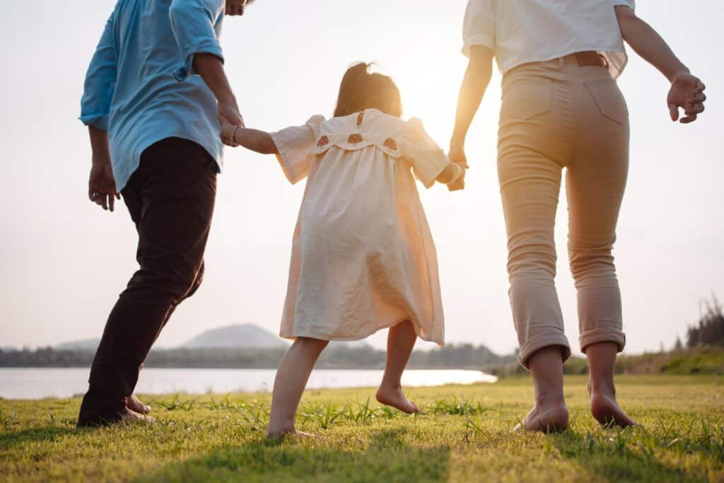 Happy Family Holding Hands Walking on Grass