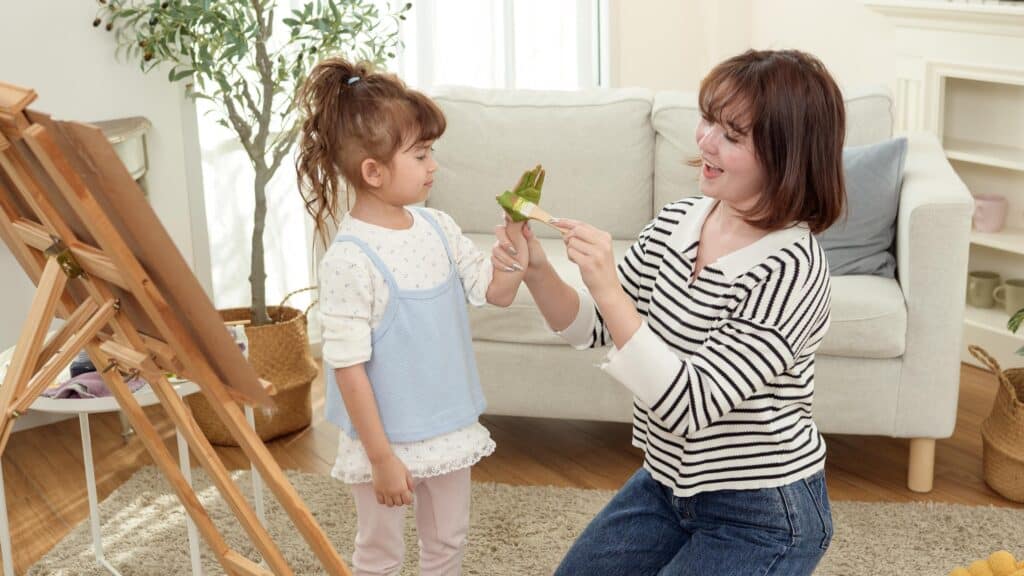 Cheerful Woman Painting Her Young Daughter's Hand at Home